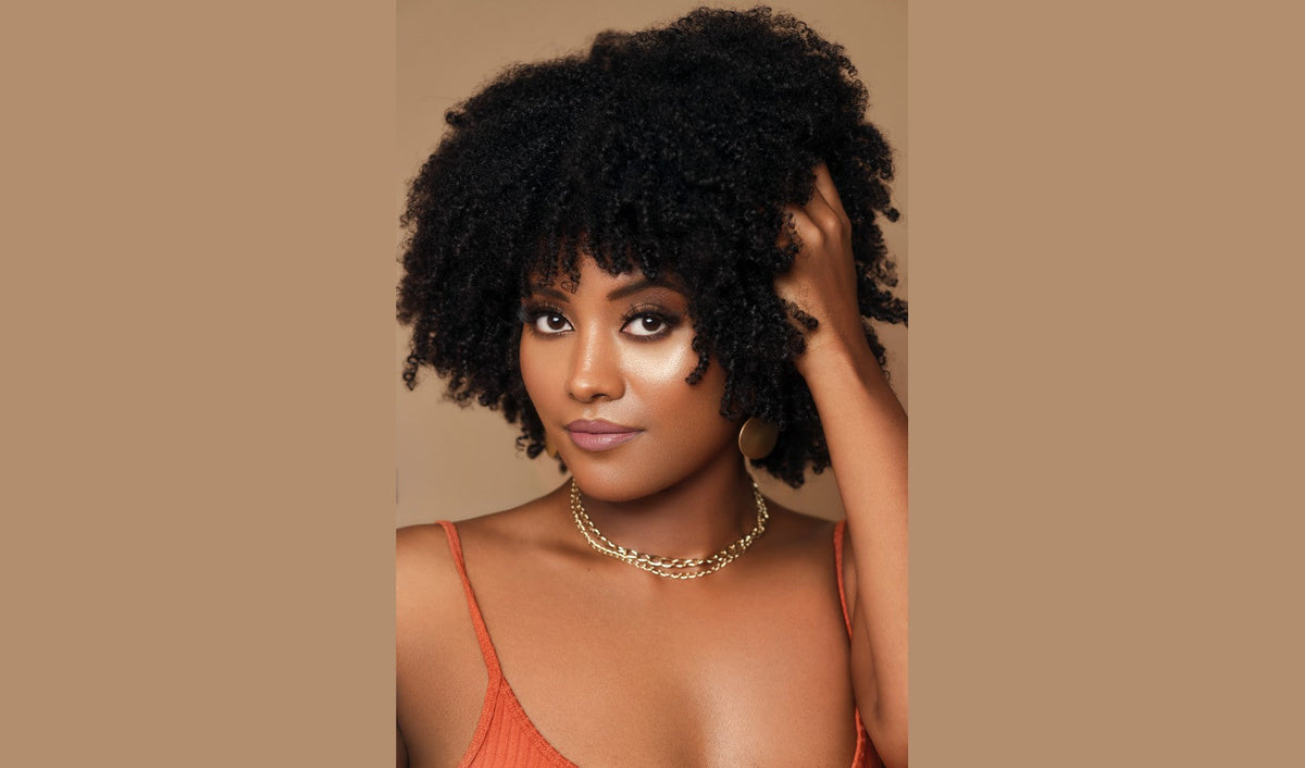 Woman with defined natural curls in a warm rust-colored outfit.