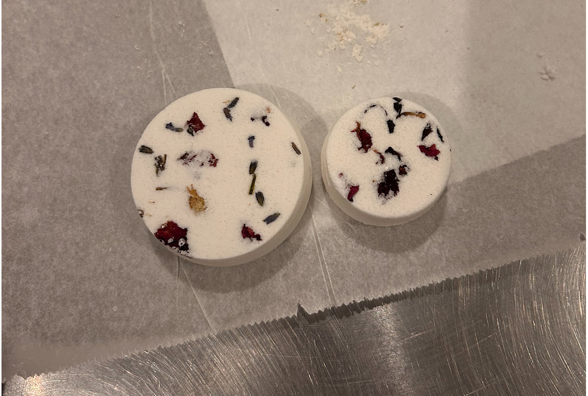 Tree Naturals Wash Day Steamies mini and deluxe sizes side by side on parchment, showing the size difference and botanicals on top.